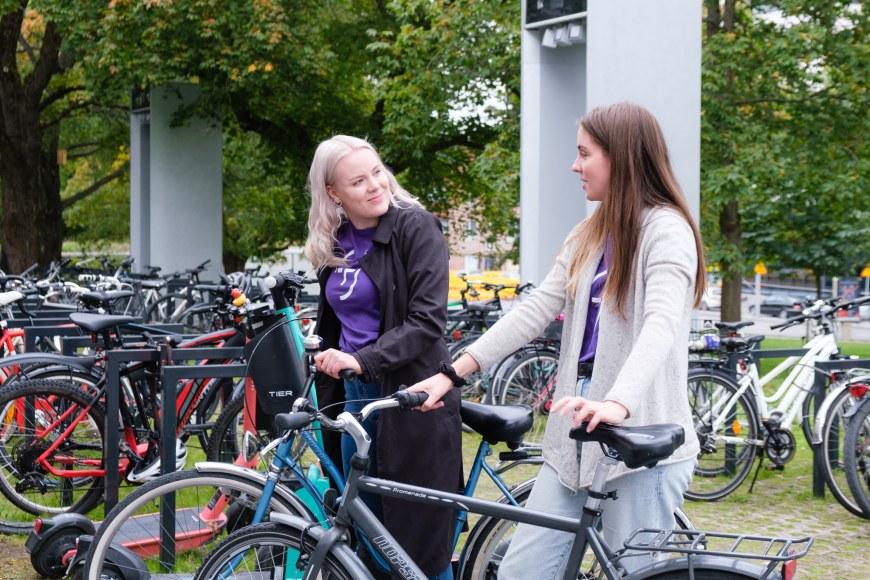 Kaksi opiskelijaa polkupyörien kanssa