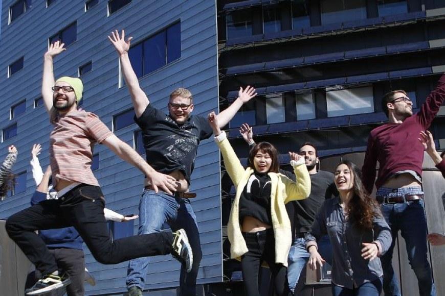 A group of international students jumping in the air in front of Hervanta campus main building.