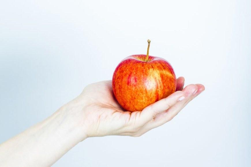 käsi pitelee punaista omenaa