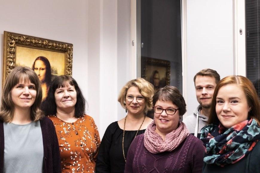 The working group of the NOW project photographed in front of the Mona Lisa painting.