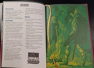 An open spread of the Runecairn book. On the left page is an overview of the game in plain text and on the right is a greenish artwork of a male viking warrior facing an elderly woman by a fire.