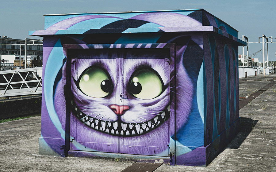 Purple Chesire cat graffiti in a cube-shaped building