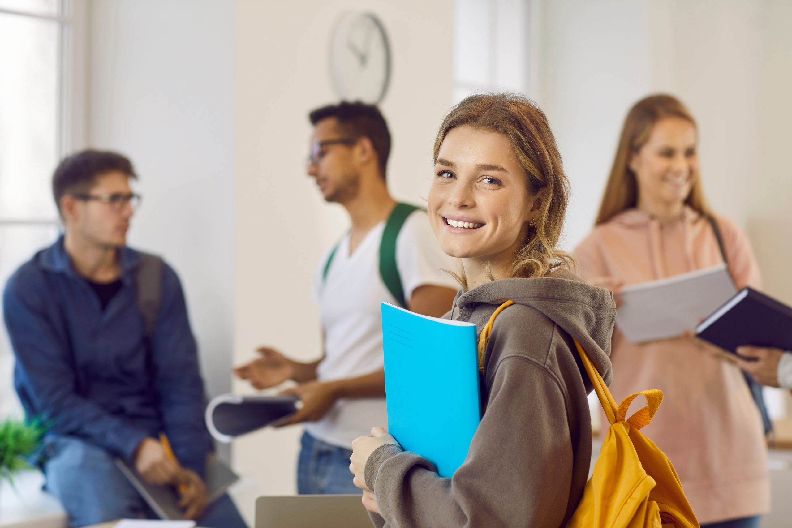 Portrait of happy university student girl holding her book and smiling at camera